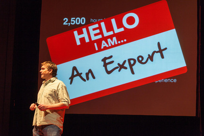 A speaker standing in front of a "hello I am an expert" backdrop