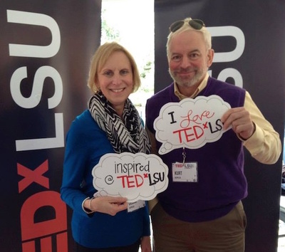 A woman and a man posing with two " I love TED x LSU" signs