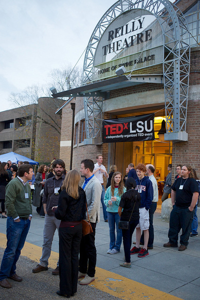 people standing in front of a building with  large Ted x LSU sign hanging on it